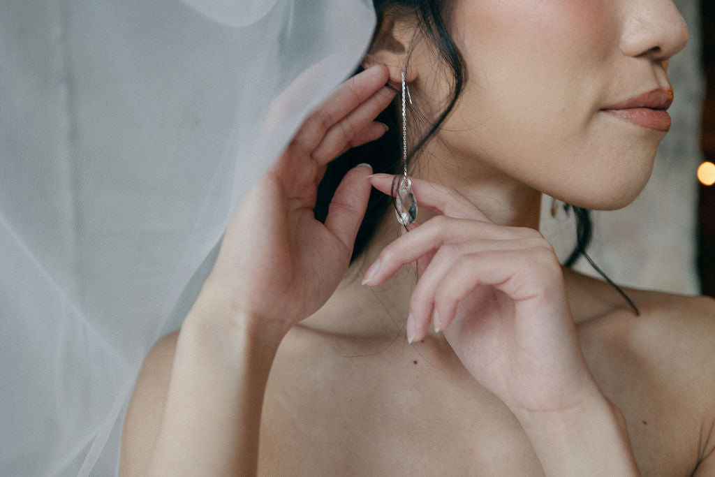 bride is wearing long crystal teardrop silver earrings with a floating veil