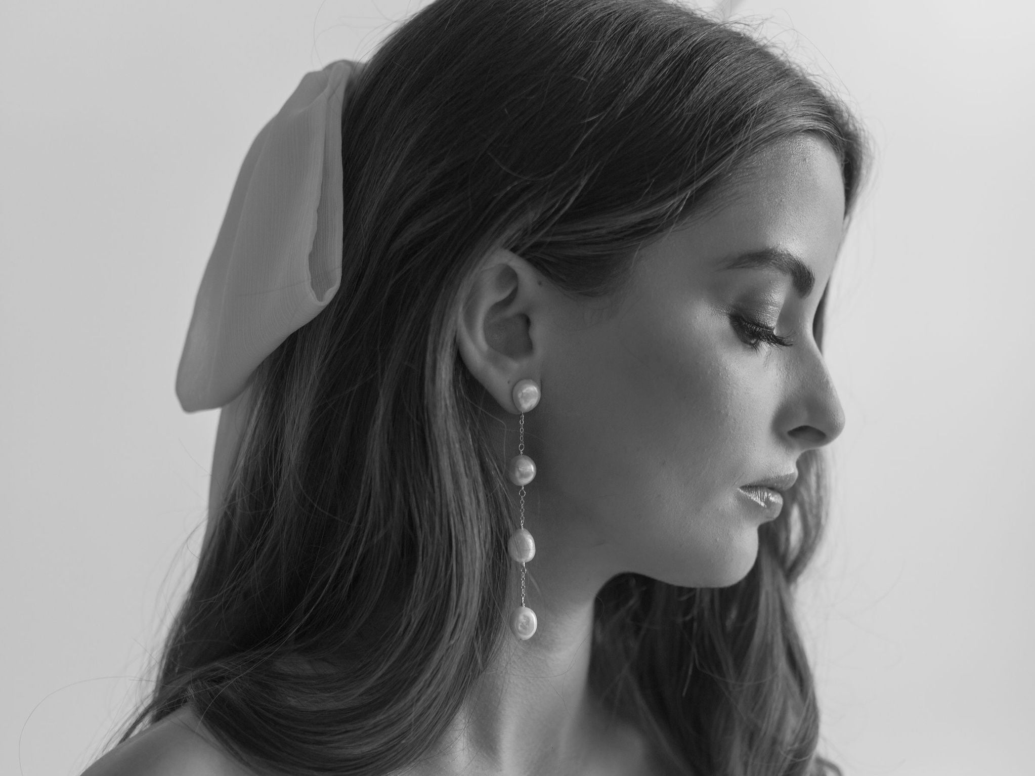 long freshwater pearl bridal earrings worn by a woman with a hair bow