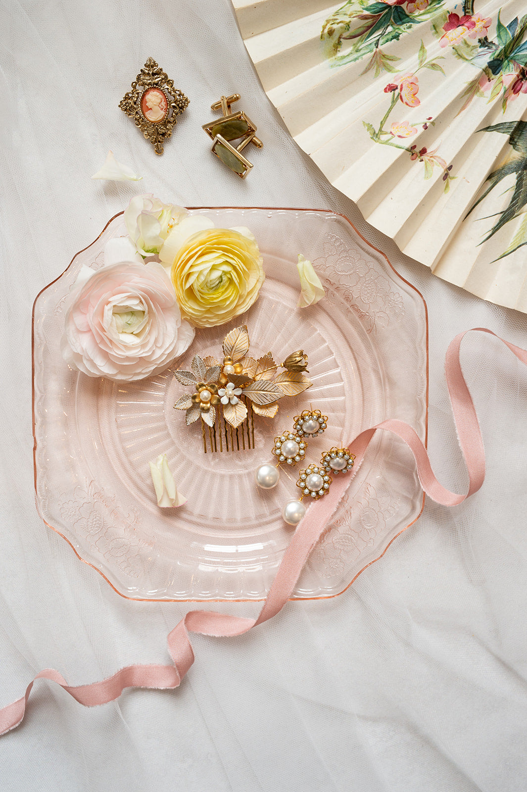 Decorative pink plate with jewelry and flowers on a light background