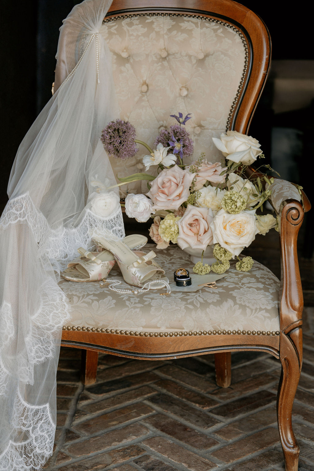 Vintage chair with wedding shoes, bouquet, and veil on a textured floor.