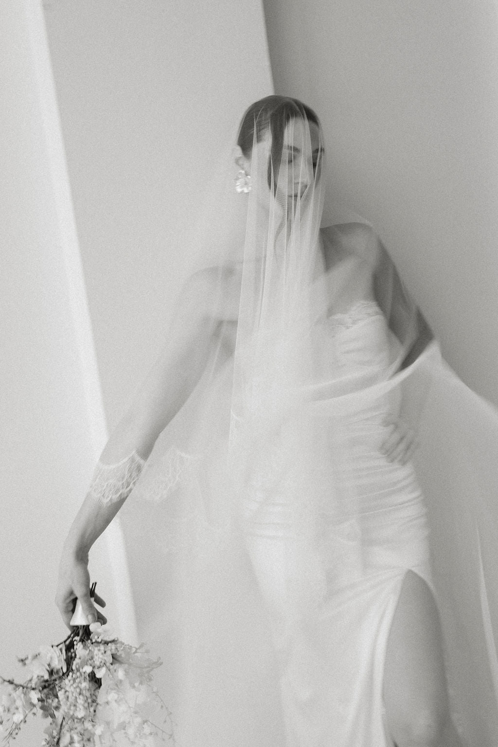 Black and white image of a bride in a wedding dress with a veil.