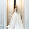 Bride in a white wedding dress with a long veil standing in a doorway.