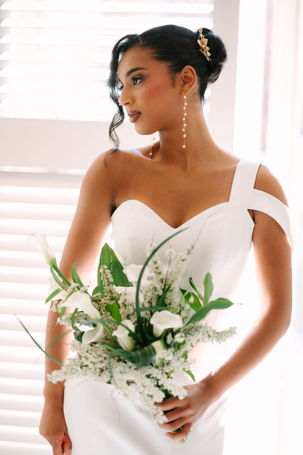 Woman in a white wedding dress holding a bouquet of flowers.