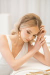 Woman with styled hair and pearl earrings in a softly lit room