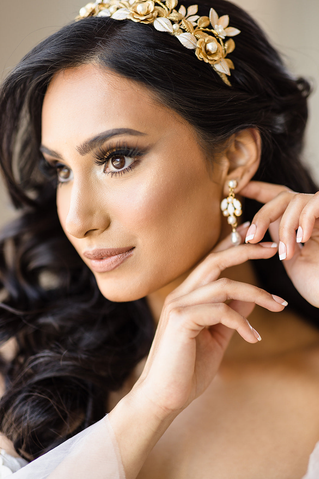 Woman wearing gold earrings and a headband with a neutral background