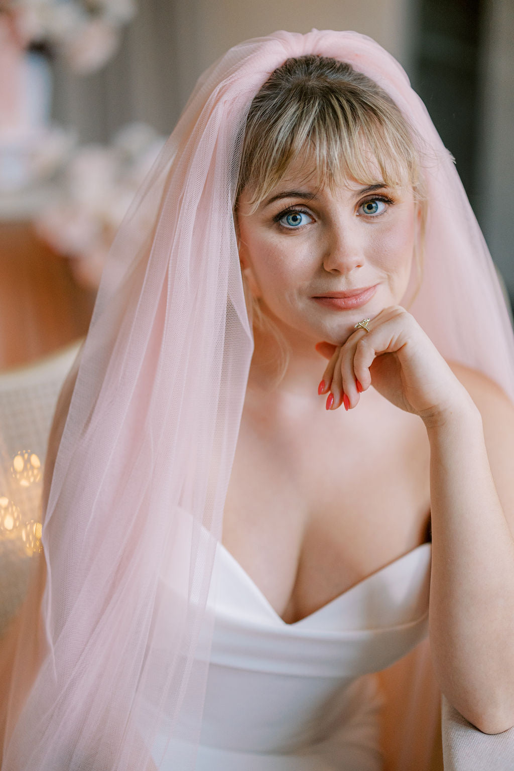 Woman wearing a white dress and pink veil with blurred background