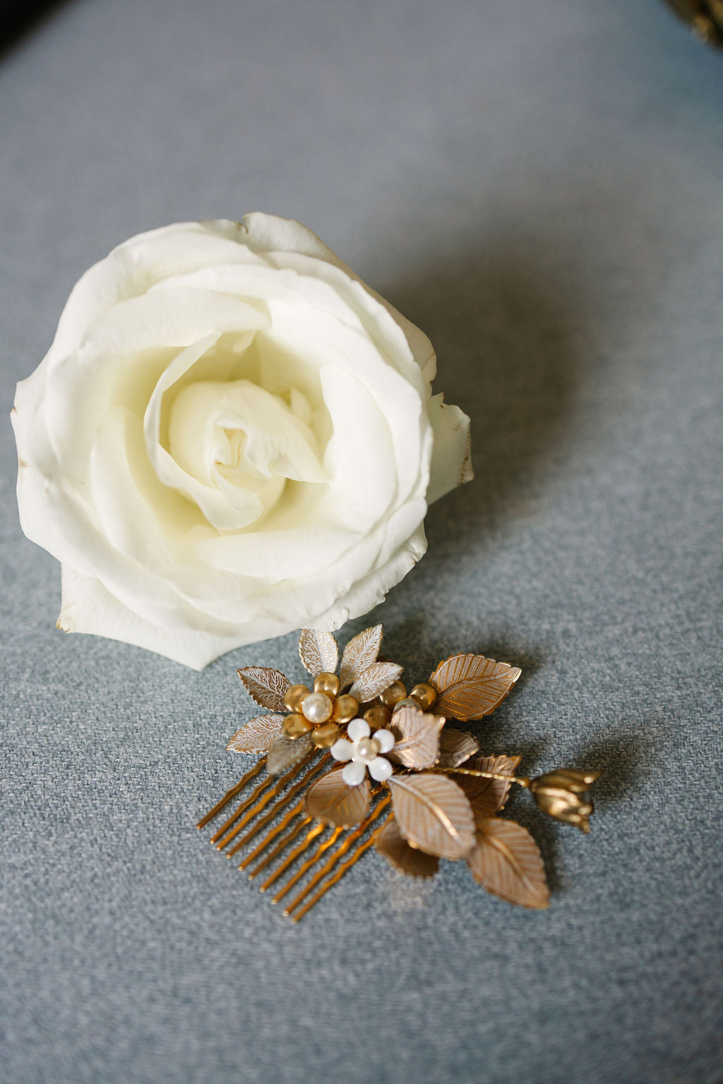 White rose and decorative gold comb on a gray background