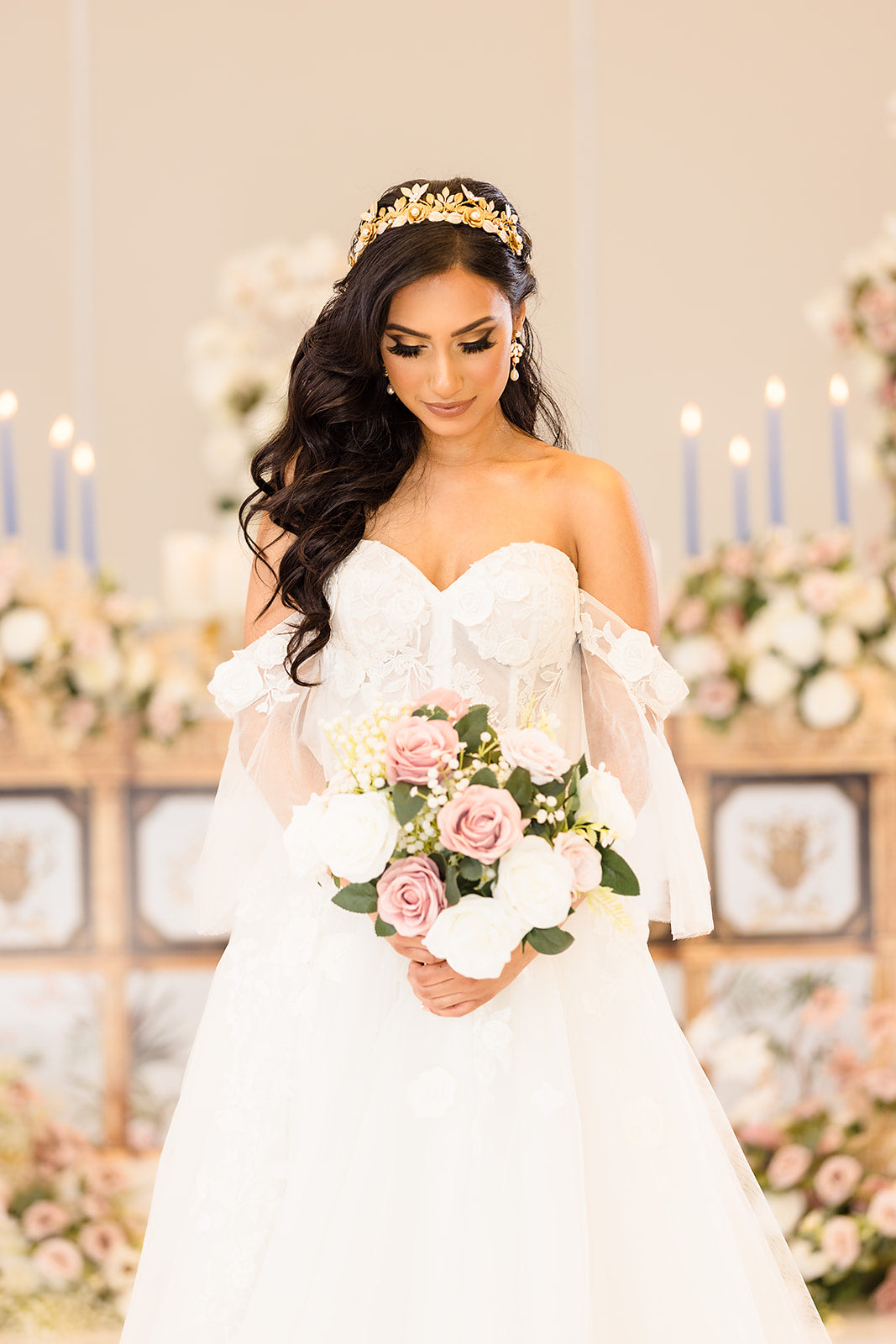 Bride in a white dress holding a bouquet of flowers with a decorated background.