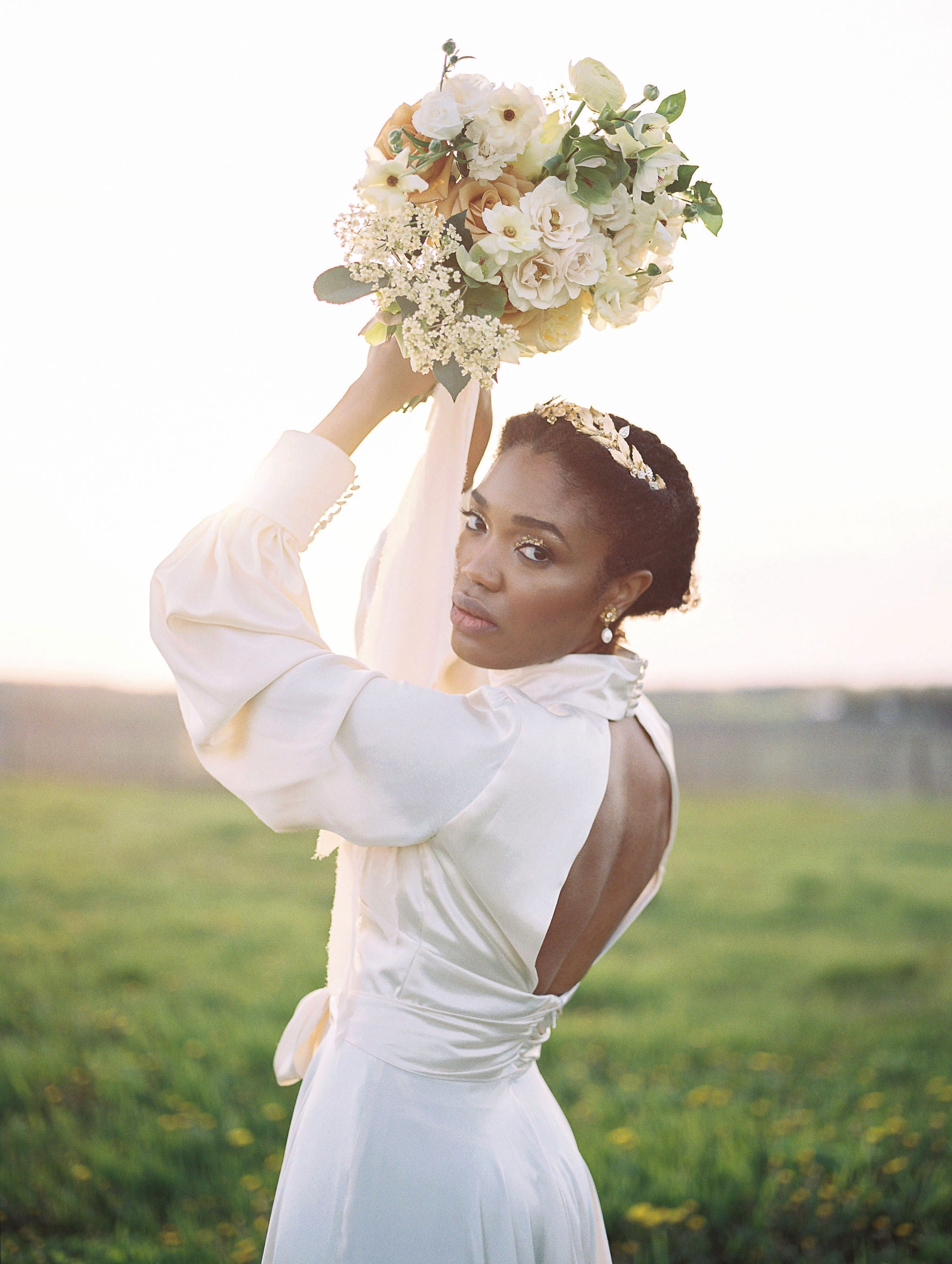Woman in a white dress holding a bouquet of flowers in a field