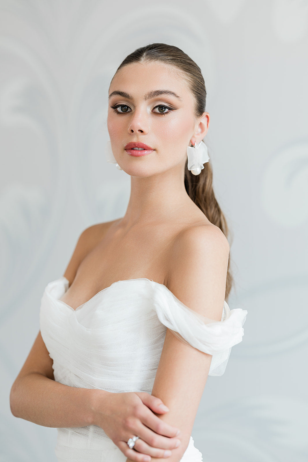 Woman wearing a white off-shoulder dress with a plain background