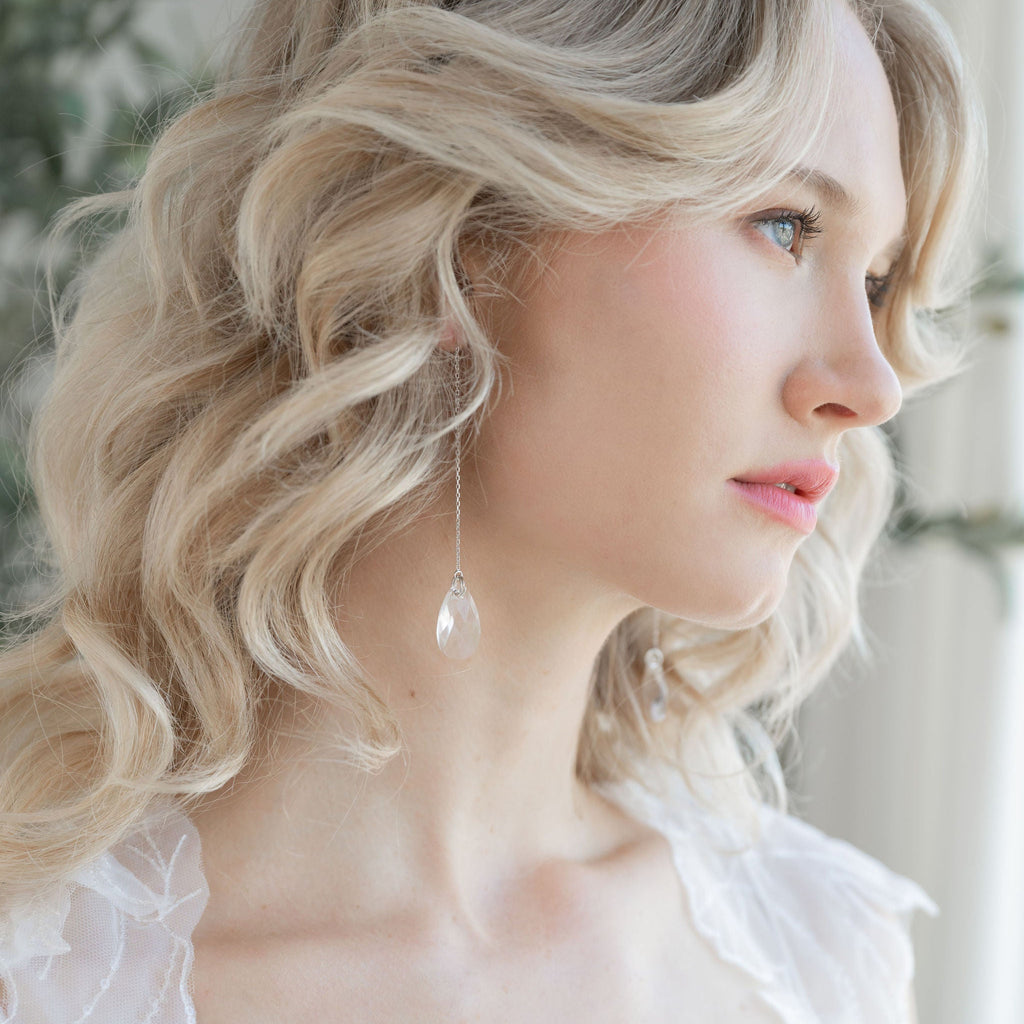Woman with styled hair and a white lace garment, possibly in a bridal setting.
