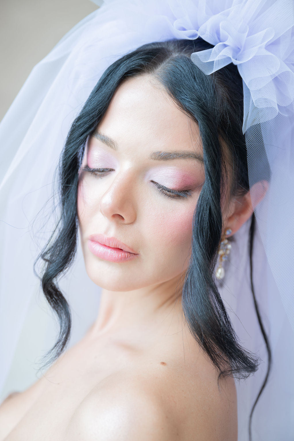 Woman with styled hair and makeup wearing a veil
