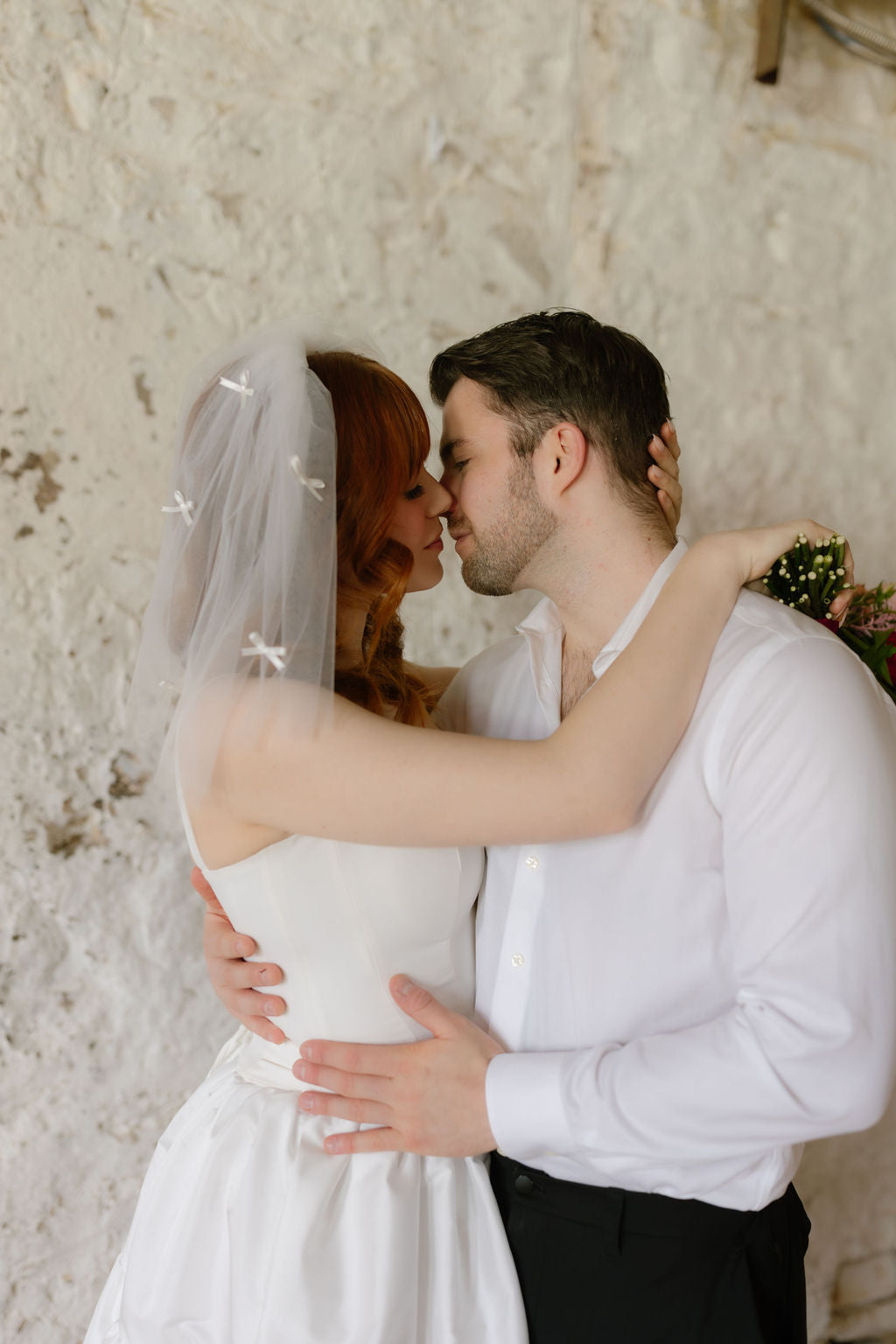 Couple embracing in front of a textured wall