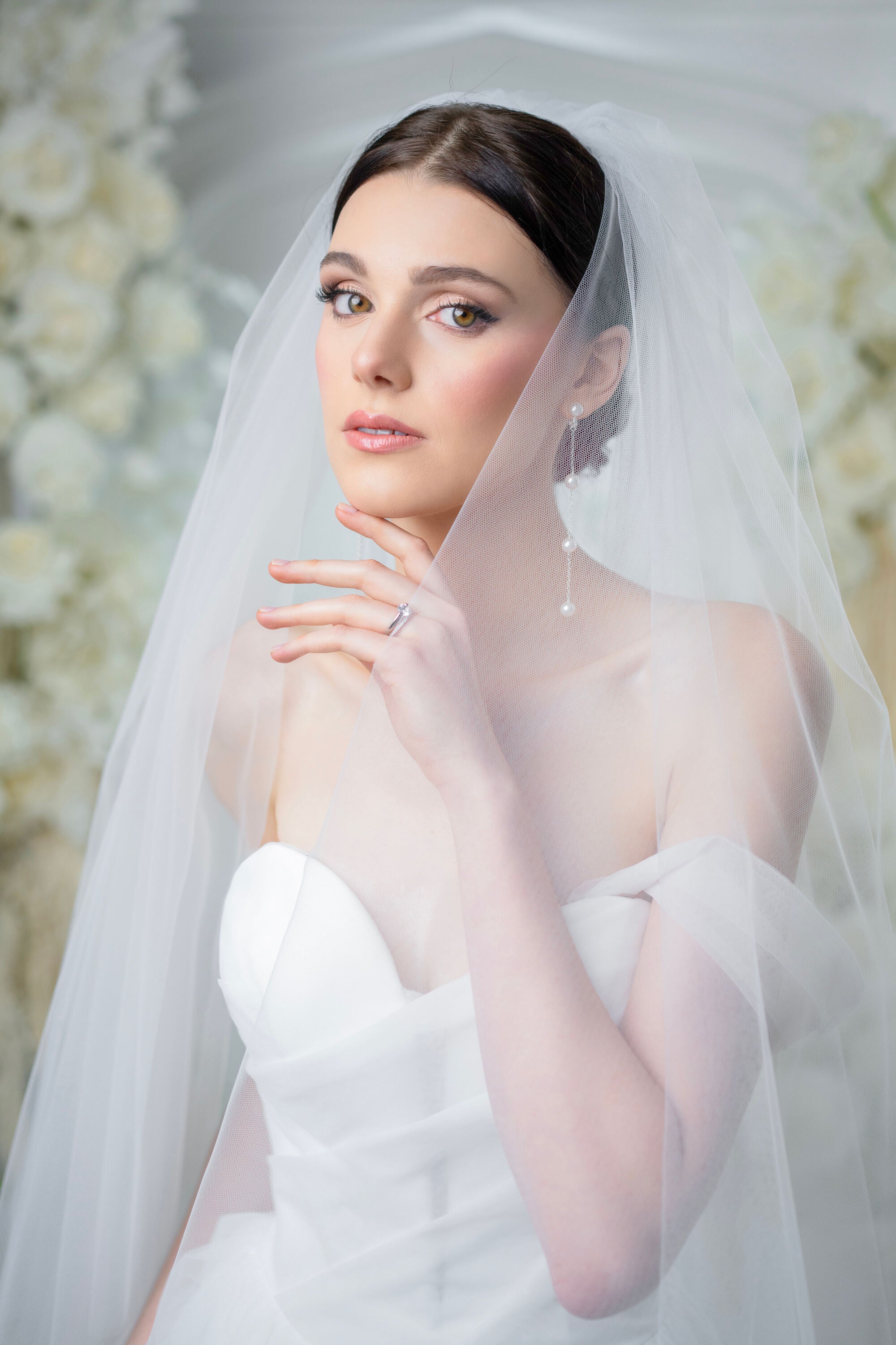 Bride wearing a white wedding dress and veil with a floral background
