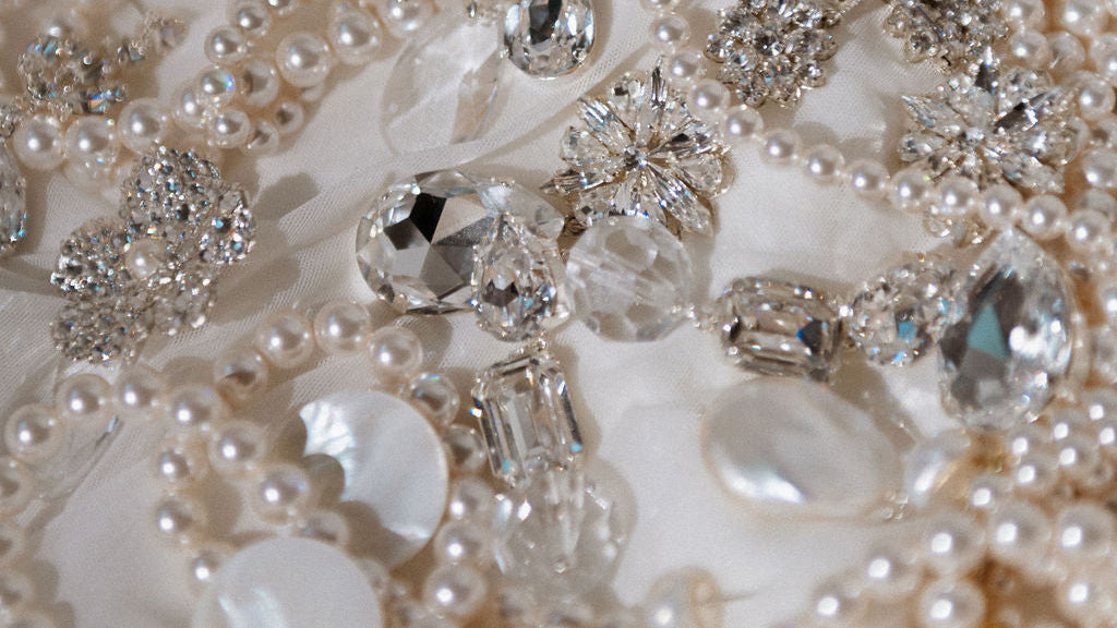 Close-up of a decorative belt with pearls and crystals on a white fabric background