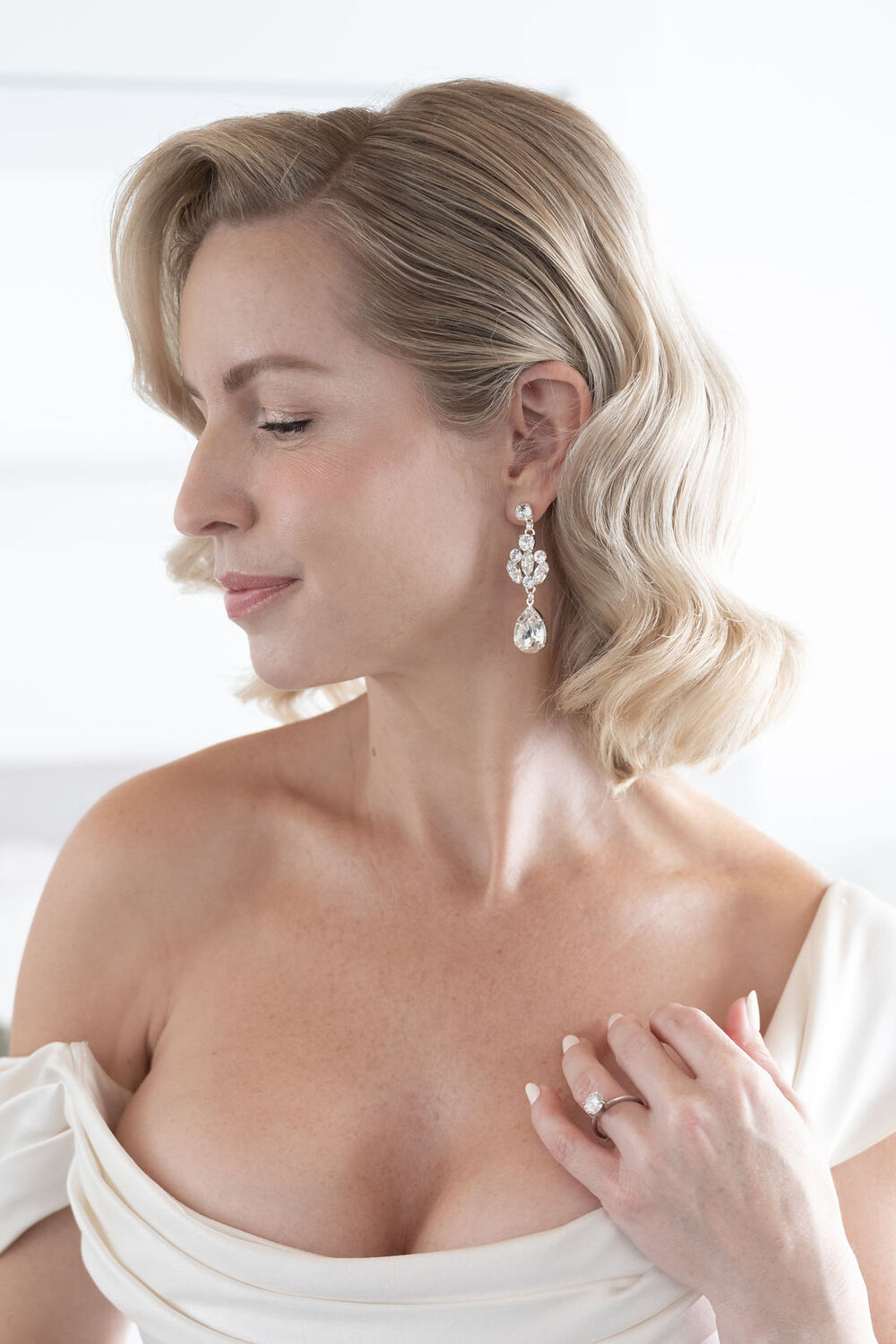 Woman wearing a white off-shoulder top with a plain background