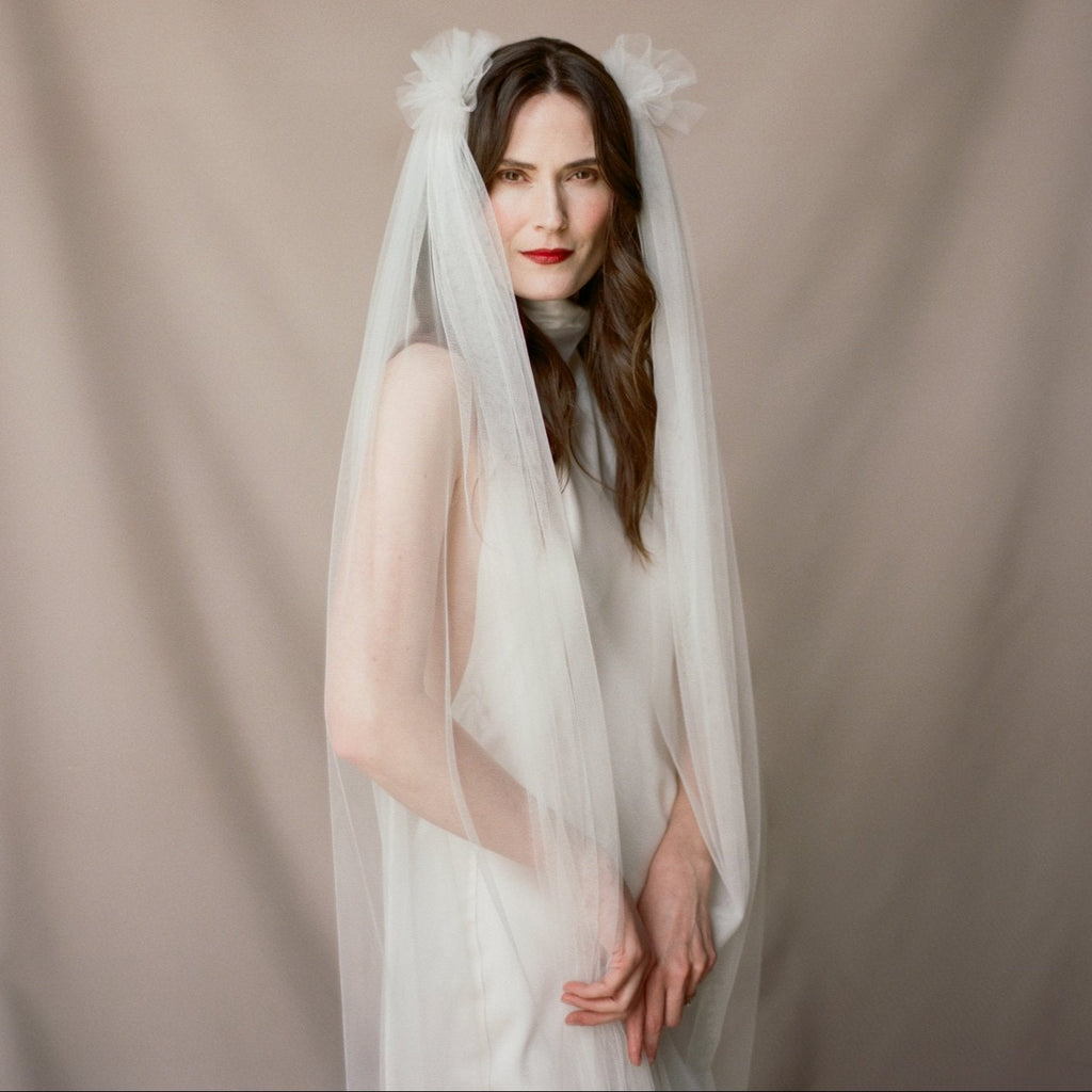 Woman wearing a white wedding dress with a veil against a beige background