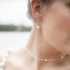 Close-up of a person wearing pearl earrings and a necklace with a blurred background