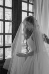 Woman in a wedding dress with a veil standing in front of a window