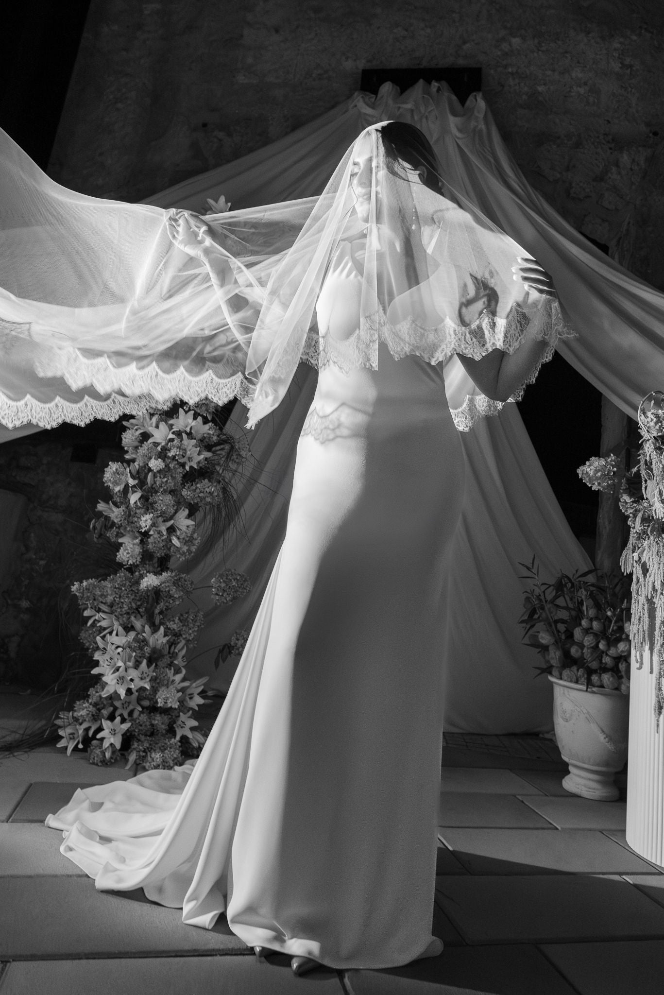 White wedding dress with a long train and veil in an elegant indoor setting.