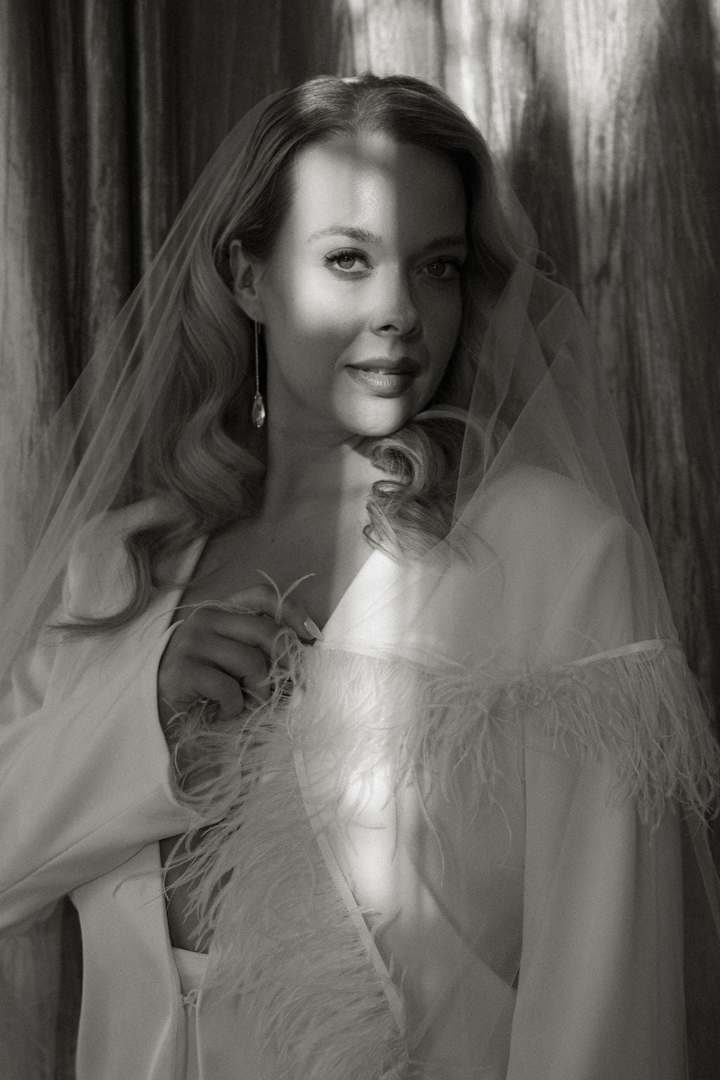 Black and white portrait of a woman wearing a light-colored dress with feather details.