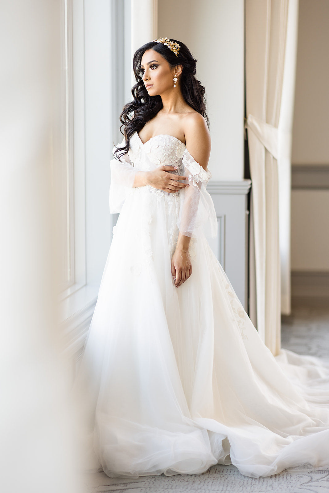 Woman in a white wedding dress standing in a elegant interior setting