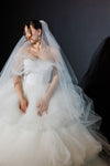 Bride in a white wedding dress with a long veil against a dark background
