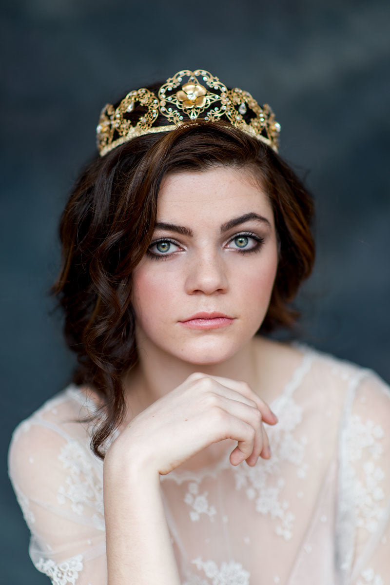 Woman wearing a gold tiara against a dark background