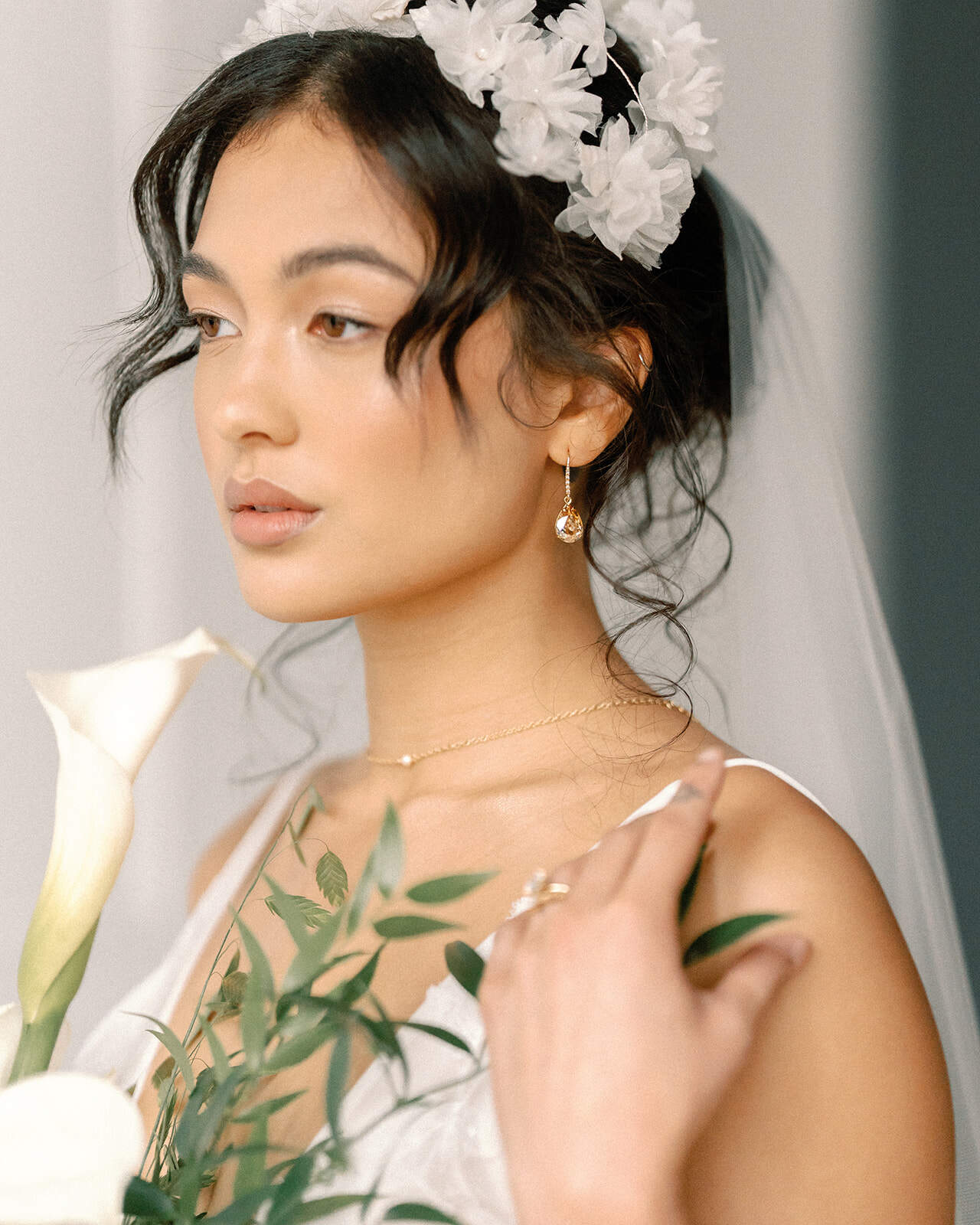 Close-up of a person wearing a teardrop earring with a bow in the background