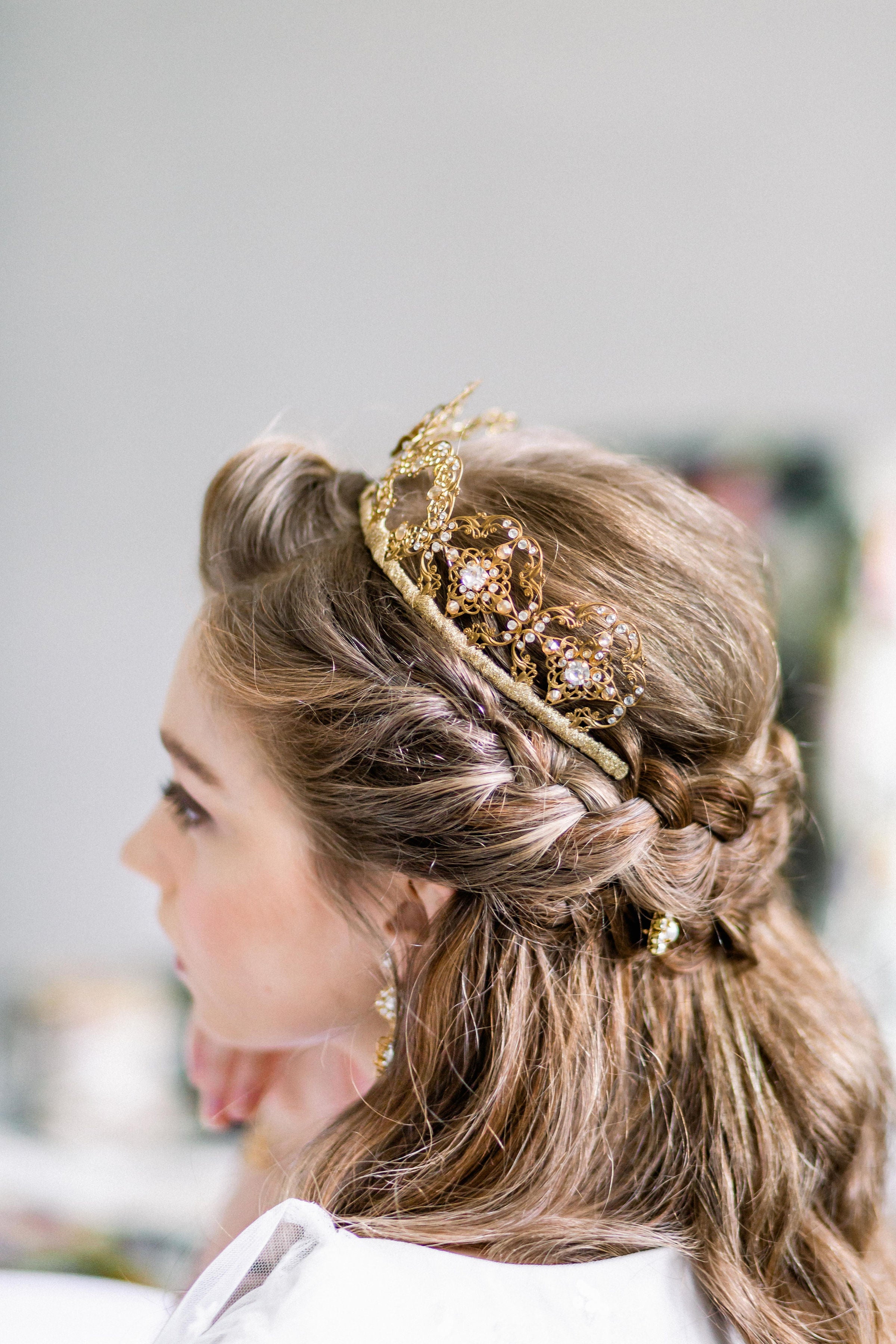 Woman with braided hair wearing a decorative gold headband against a blurred background