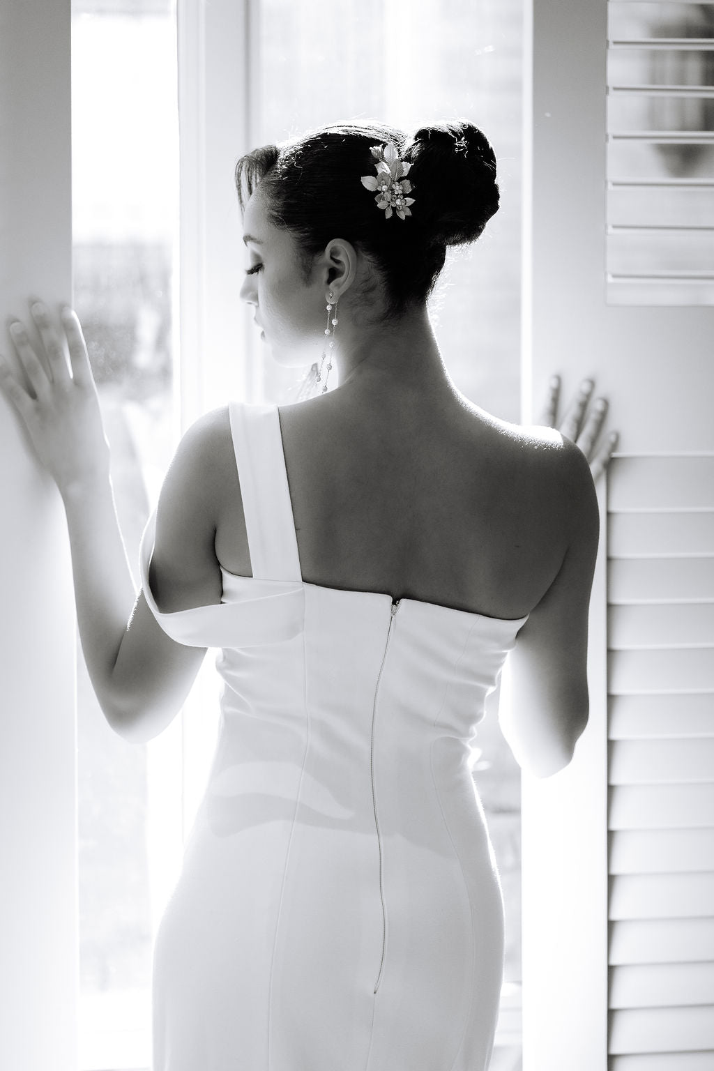 Woman in a white dress standing by a window with a blurred background