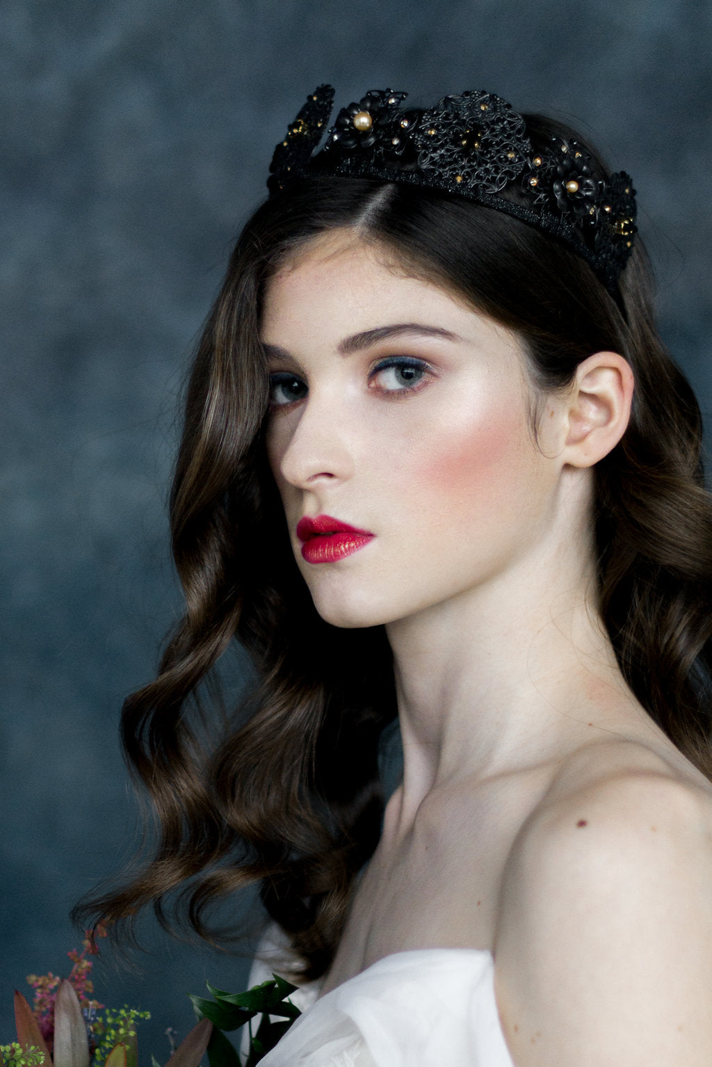 Woman wearing a black jeweled tiara against a dark background