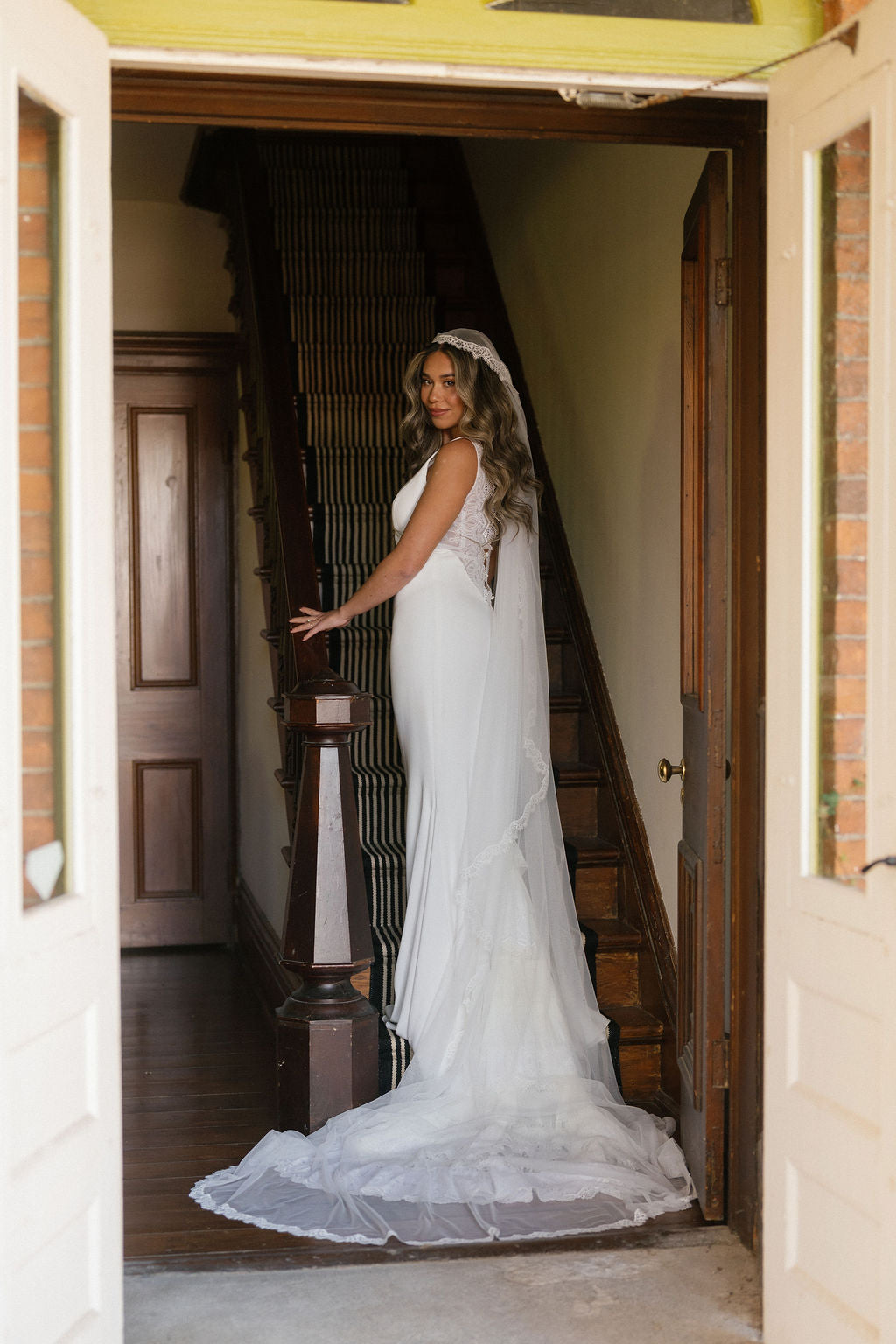Woman in a white wedding dress standing in a doorway.
