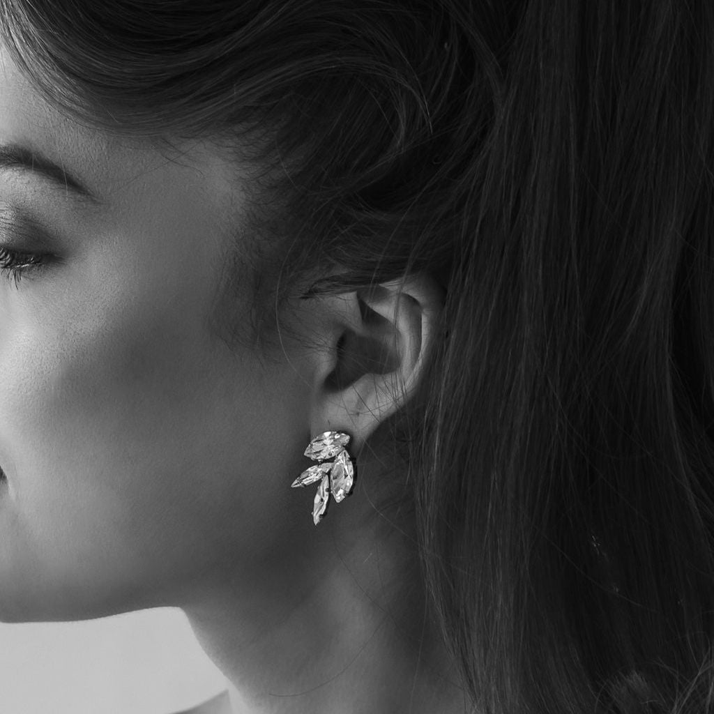 Close-up of a woman wearing a leaf-shaped earring with a blurred background