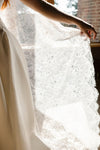 Close-up of a person wearing a white lace dress with a blurred background