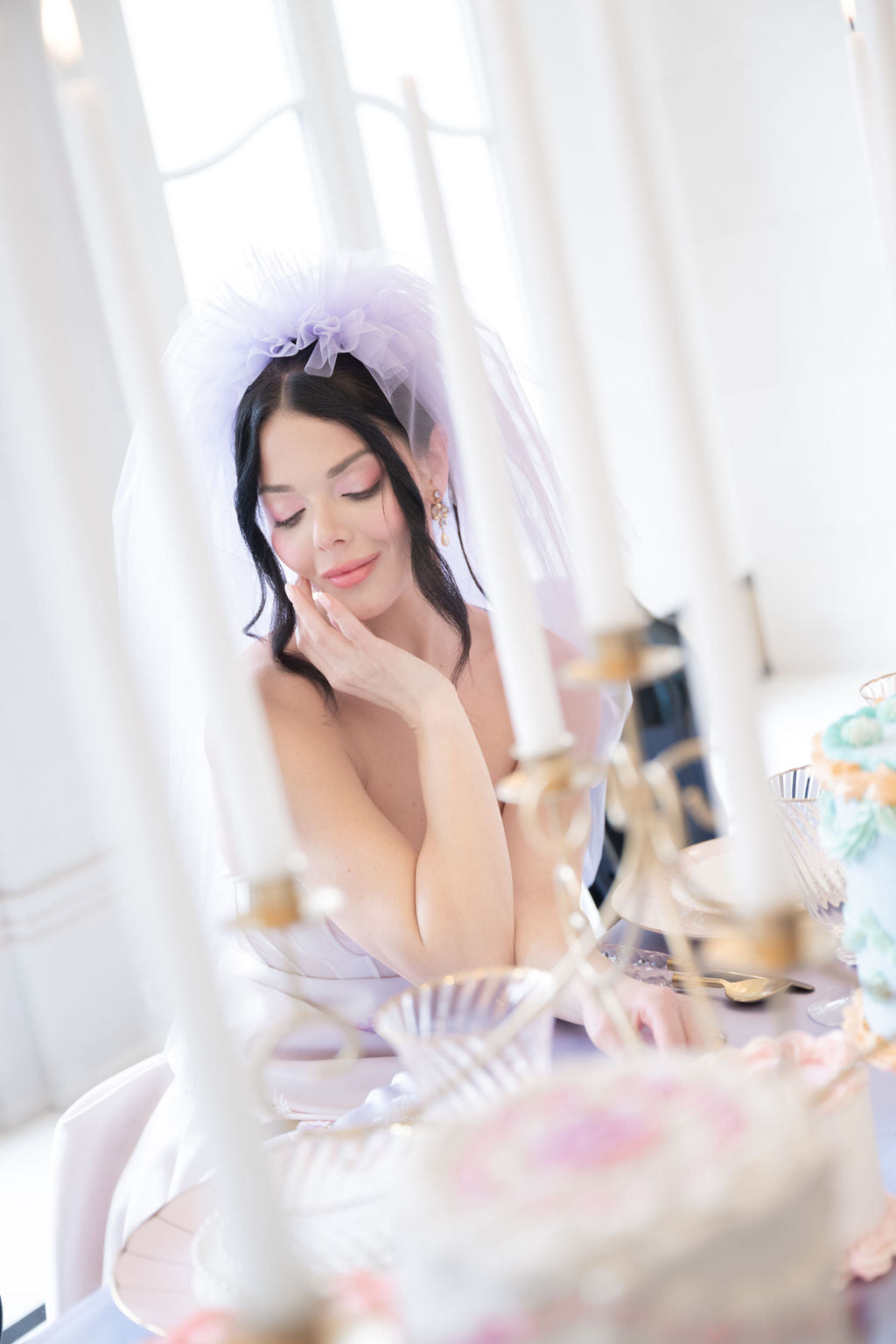 Woman in a white dress with a veil sitting on a swing, surrounded by flowers.