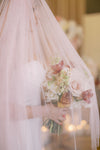 Bride holding a bouquet under a veil with blurred lights in the background
