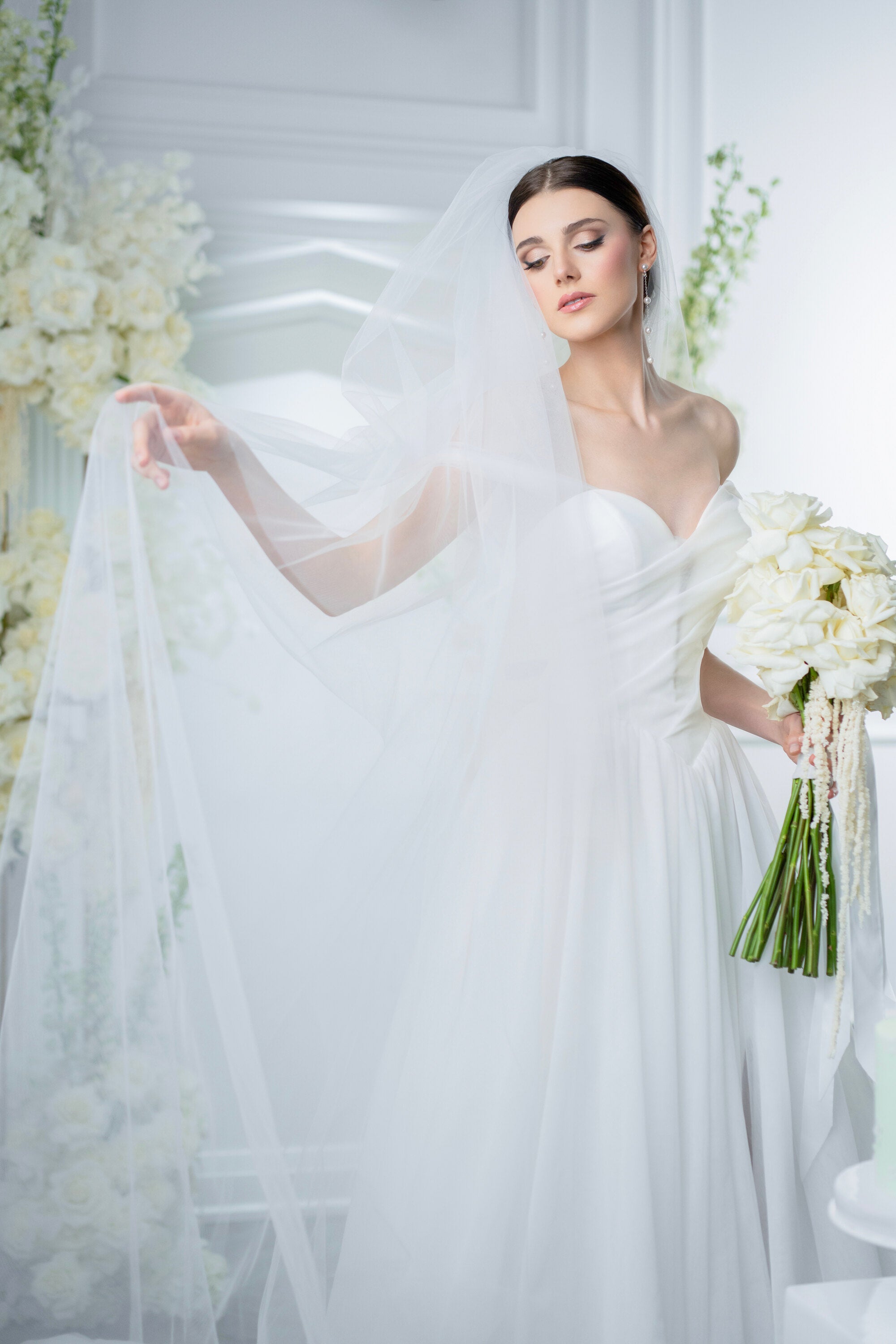 Bride in a white wedding dress holding a bouquet with a white veil.