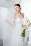 Bride in a white wedding dress holding a bouquet with a white veil