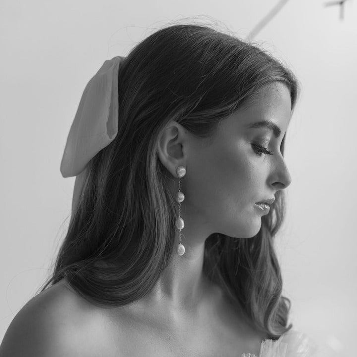 Black and white portrait of a woman wearing earrings with a plain background