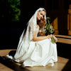 Woman in a white wedding dress holding flowers in a softly lit room.