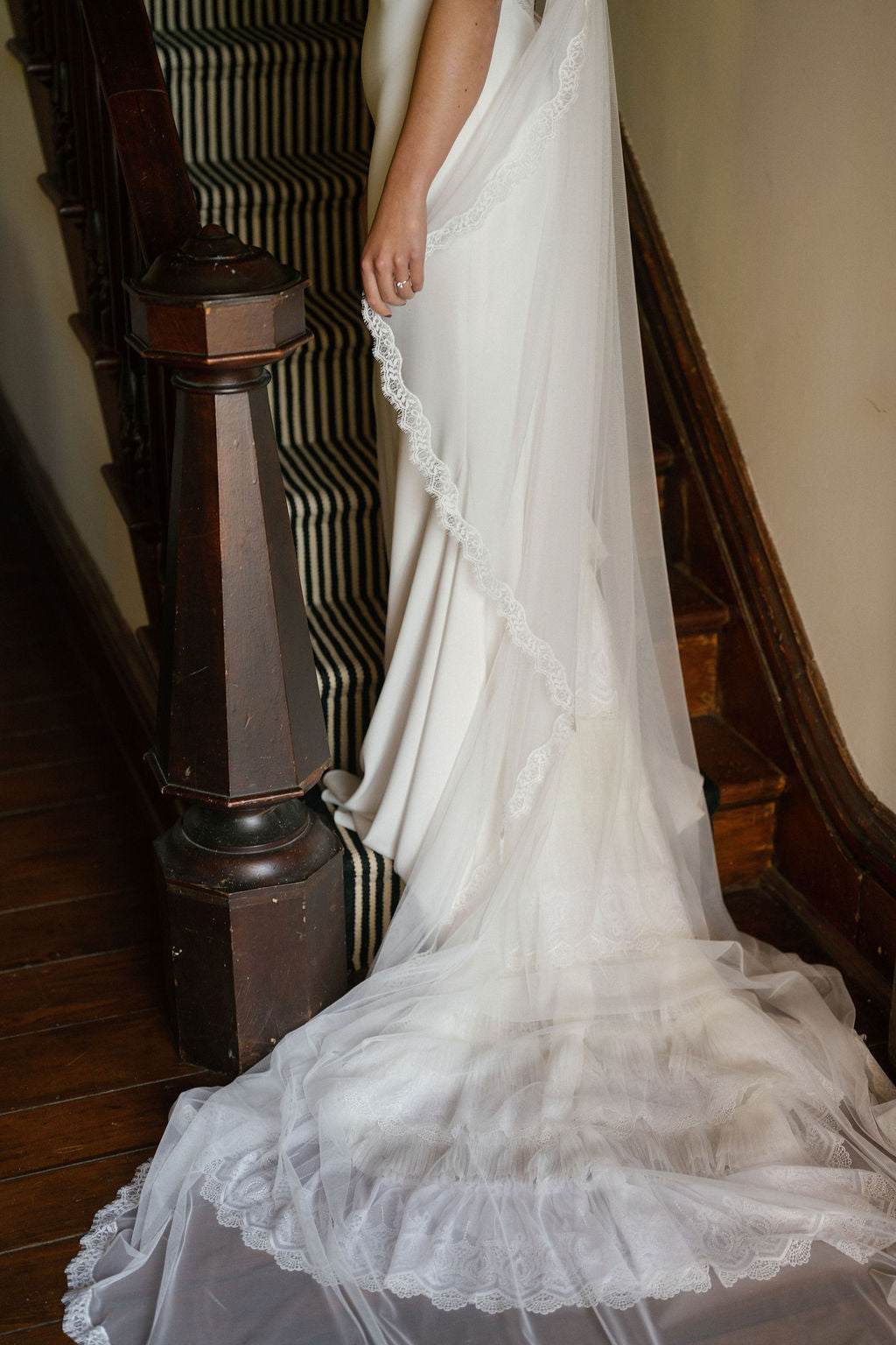 White lace dress with a long train on a staircase