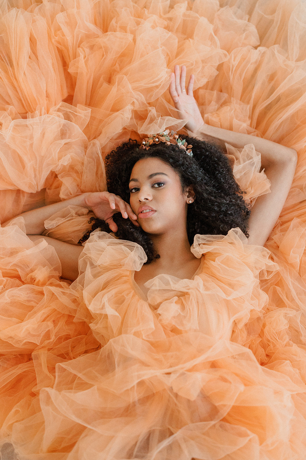 Woman in a flowing peach dress surrounded by orange fabric