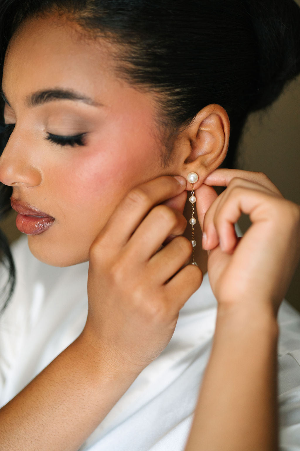 Woman adjusting a pearl earring with a blurred background