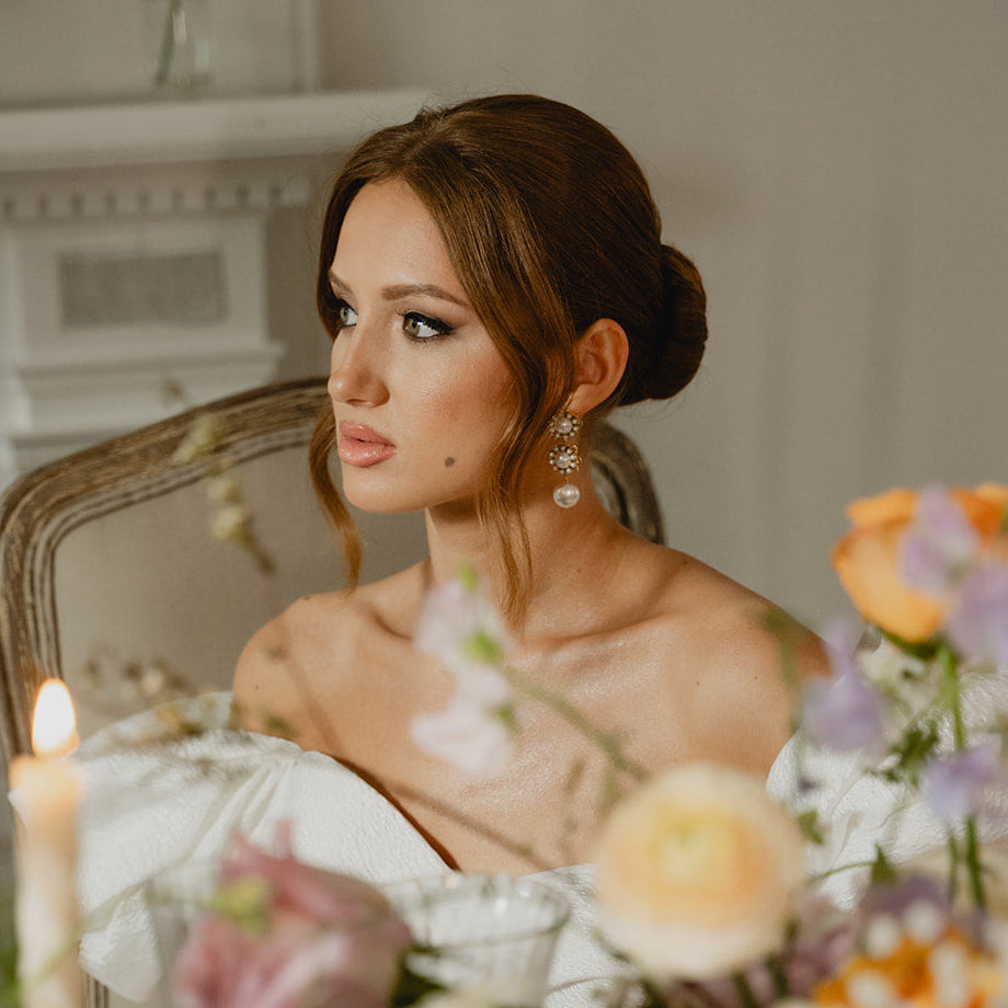 Woman sitting at a table with floral arrangements and candles in a formal setting