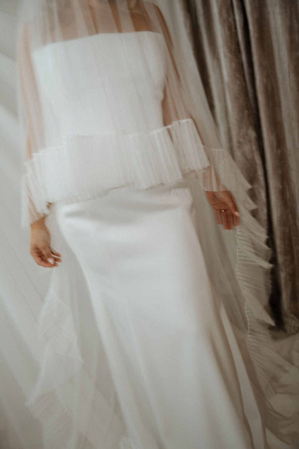 White wedding dress with sheer overlay against a neutral background