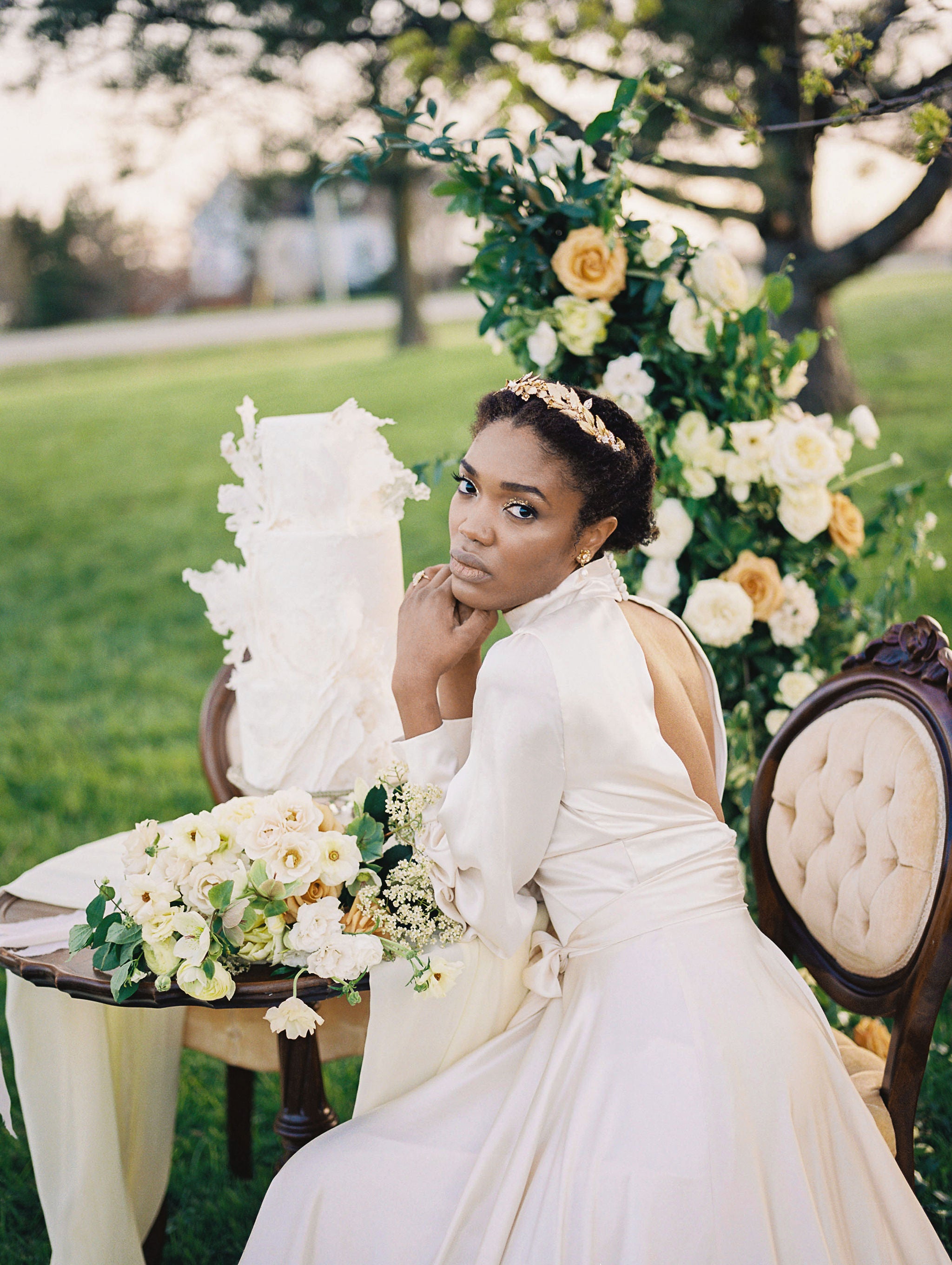 Woman in a white dress sitting outdoors with floral decorations