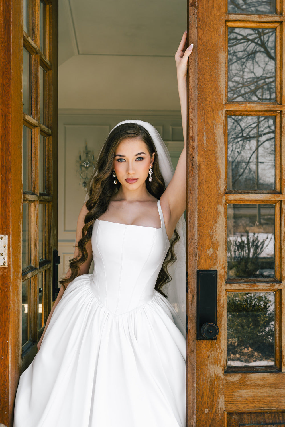 Bride in a white wedding dress standing in a doorway.