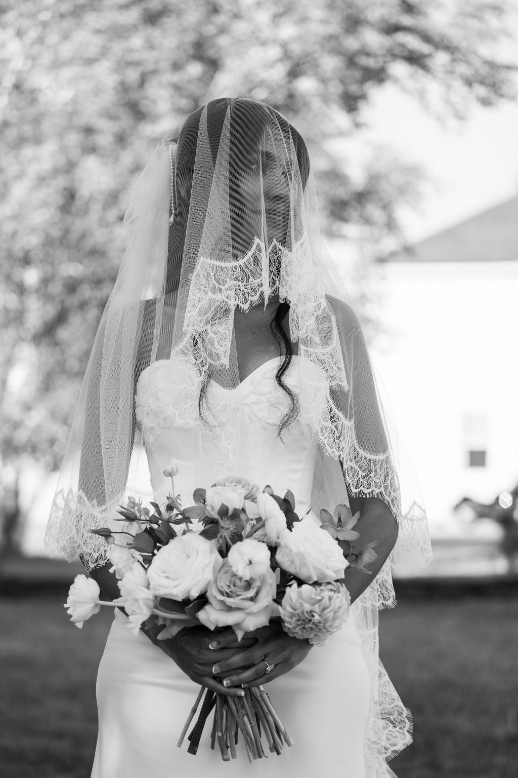 Black and white photo of a bride holding a bouquet with a blurred background