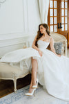 Woman in a white wedding dress sitting on a vintage chair in a elegant room.